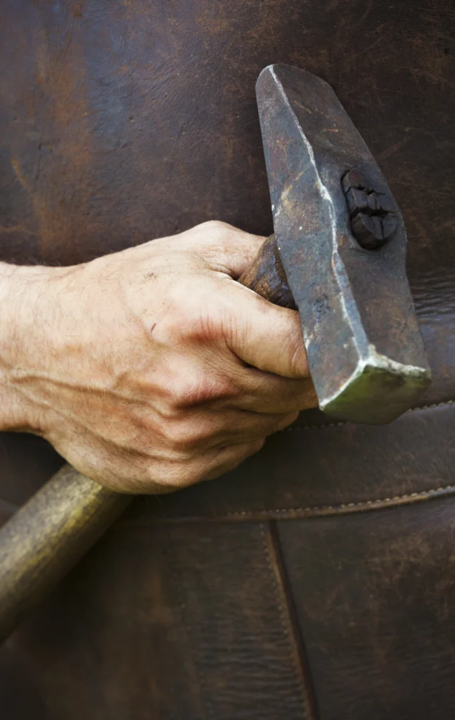 Mann in Lederschürze mit einem Hammer in derHand