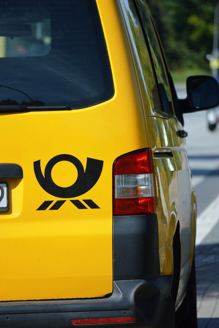 Heck eines gelben Postzustellfahrzeugs mit Posthorn-Logo. Foto: neelam279 / pixabay.com